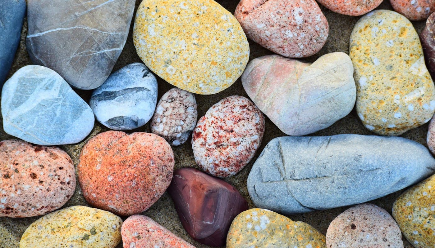 Smooth stones of many different colours and shapes, resting together