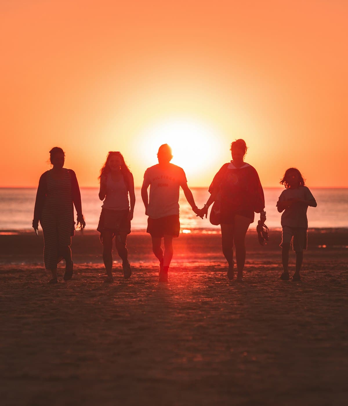A family silhouetted on the beach at sunset
