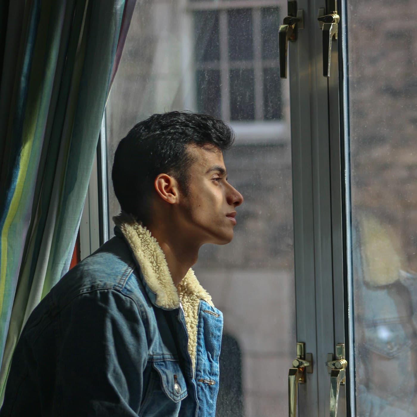 A young man looking thoughtfully out of a window